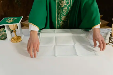 Green liturgical vestments and a chalice as an altar is prepared