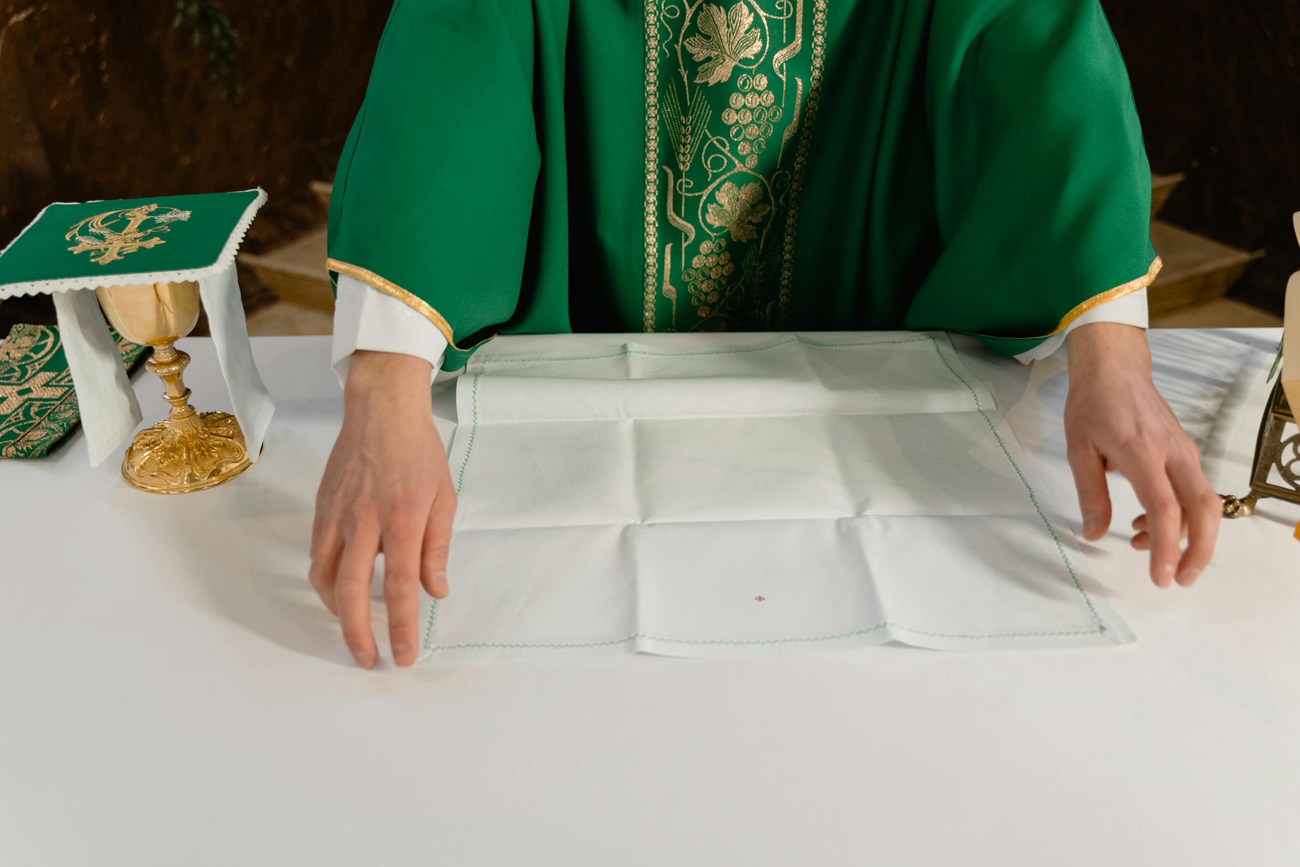 Green liturgical vestments and a chalice as an altar is prepared