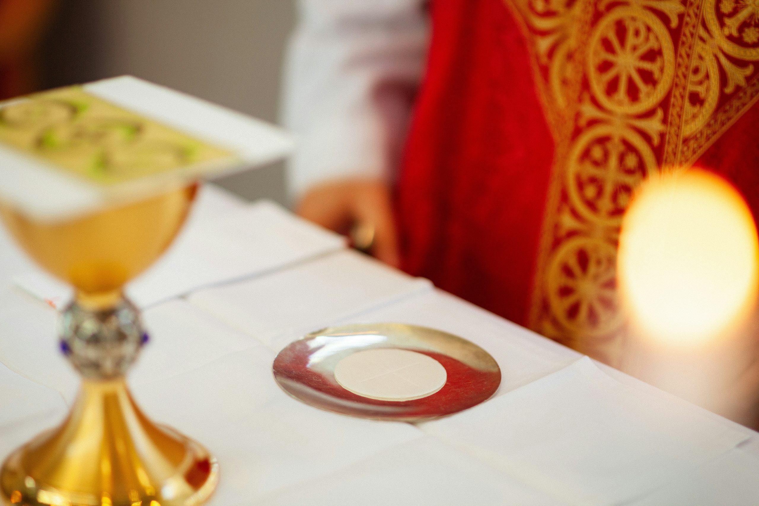 Chalice, paten and candle at the Eucharist, with red and gold vestments